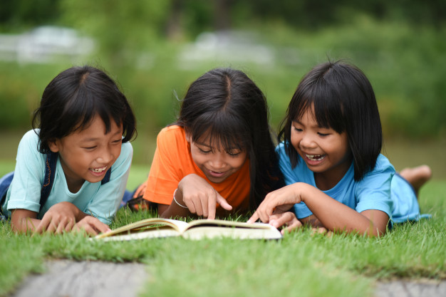 group-children-lying-reading-grass-field